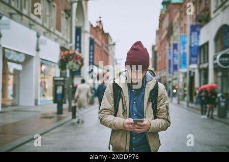 Camminare, strada e telefono dell'uomo con ricerca, direzione e viaggio a Londra in vacanza. App di localizzazione, turismo e viaggio con navigazione, testo e. Foto Stock