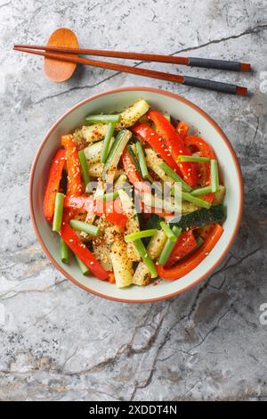 Mescolare le zucchine estive, le cipolle verdi e il peperone da vicino in un recipiente sul tavolo. Vista dall'alto verticale Foto Stock