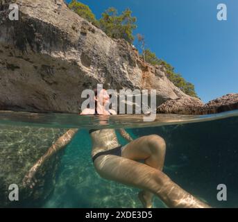 Le giovani donne in vacanza si divertono a galleggiare su una spiaggia di acqua cristallina di Antalya in Turchia. Bella donna asiatica che nuota a braccia aperte. Rilassati e tra Foto Stock