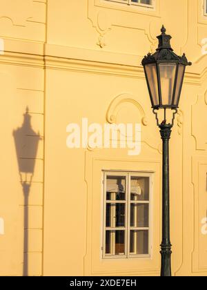 Un antico lampione e la sua ombra sulla facciata di una vecchia casa con una finestra a Praga, Repubblica Ceca, Europa. Foto Stock