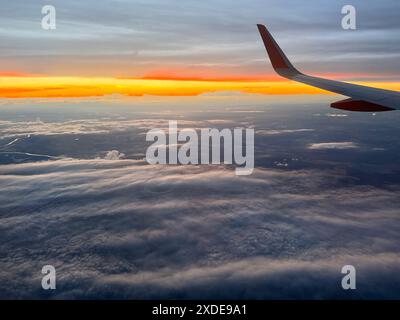 Spettacolare vista del tramonto dalla finestra dell'aereo durante il volo sopra le nuvole Foto Stock