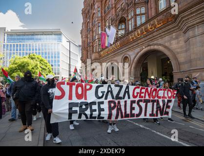 Manchester, Regno Unito. 22 giugno 2024. I manifestanti marciano oltre il Midland Hotel Peters Street. Proteste di guerra palestinesi a Gaza a Manchester nel Regno Unito. I manifestanti hanno marciato da Piazza San Pietro attraverso il centro della città. Gli striscioni includevano messaggi che chiedevano di fermare il genocidio di gaza da parte di Israele e di liberare la Palestina. I manifestanti includevano membri della comunità LGBGT che portavano striscioni che esprimevano il loro sostegno ai palestinesi. La Barclays Bank su Market Street rimane impressa da cartelli che si scusano. Manchester Regno Unito. Crediti: GaryRobertsphotography/Alamy Live News Foto Stock