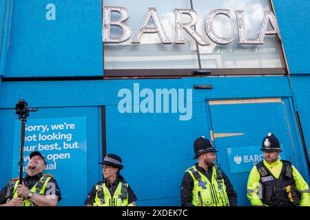 Manchester, Regno Unito. 22 giugno 2024. E' salito sulla Barclays Bank sorvegliata dalla polizia in Market Street. Proteste di guerra palestinesi a Gaza a Manchester nel Regno Unito. I manifestanti hanno marciato da Piazza San Pietro attraverso il centro della città. Gli striscioni includevano messaggi che chiedevano di fermare il genocidio di gaza da parte di Israele e di liberare la Palestina. I manifestanti includevano membri della comunità LGBGT che portavano striscioni che esprimevano il loro sostegno ai palestinesi. La Barclays Bank su Market Street rimane impressa da cartelli che si scusano. Manchester Regno Unito. Crediti: GaryRobertsphotography/Alamy Live News Foto Stock