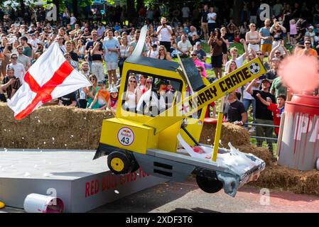 Alexandra Palace, Londra, Regno Unito. 22 giugno 2024. Bizzarri e stravaganti disegni di scatole di sapone hanno corso lungo il percorso collinare attraverso Alexandra Park sotto la Ally Pally e su salti che hanno testato i design e le abilità di guida delle squadre. Un gran numero di carrelli fatti a mano alimentati esclusivamente dalla gravità e una spinta degli equipaggi dalla cima della collina tentarono di stabilire il tempo più veloce. Molti sono venuti a soffrire prima del traguardo, che è stato subito dopo una rampa di salto che ha lanciato i carri più veloci in alto. Squadra No Kane, No Gain. Harry Crane, Harry Kane gioco di parole Foto Stock