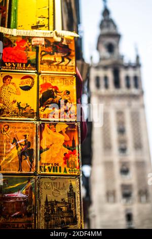 Cartoline tradizionali colorate da Siviglia con la torre la Giralda sfocata sullo sfondo, catturando la cultura e il patrimonio spagnolo. Foto Stock