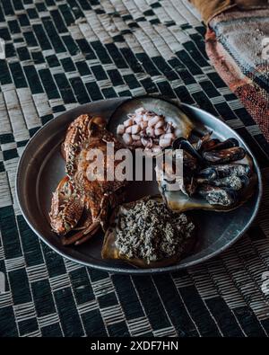 Un piatto di pesce fresco che include granchio, calamari, cozze e una prelibatezza locale alla Laguna di Detwah, Socotra, Yemen Foto Stock