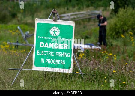 Segnale di pericolo per la pesca elettrica in corso, Agenzia per l'ambiente, elettropesca per sondare la popolazione ittica nel fiume, Fittleworth, West Sussex, Inghilterra, Regno Unito Foto Stock