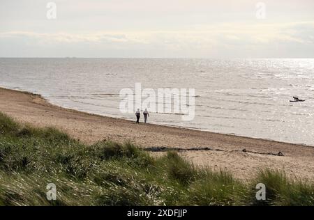 Una coppia distante che cammina su una spiaggia Foto Stock