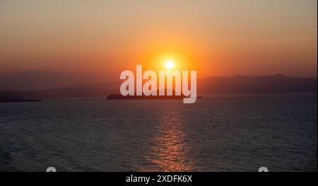 Grecia. Tramonto su un piccolo isolotto roccioso e sul mare Egeo dalla collina di Akrotiri e dalle tombe di Venizelos, la Canea e l'isola di Creta Foto Stock