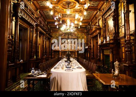 Sinaia, Romania - 26 agosto 2022: Sala da pranzo con tavolo servito ricoperto di tovaglie bianche all'interno del castello di Peles. Il ricco interno del Peles Foto Stock