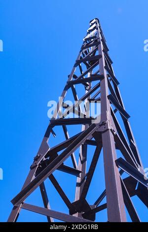 Vecchio albero in metallo con un'asta di fulmine su uno sfondo di cielo blu, vista dal basso. Foto Stock