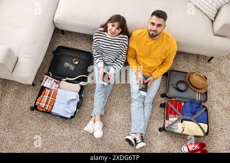 Coppia con passaporti e biglietti vicino alle valigie al piano interno, vista dall'alto Foto Stock