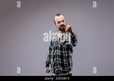 Un uomo adulto con la barba stringe i pugni e mostra aggressività, esprimendo emozioni negative come rabbia e rabbia Foto Stock