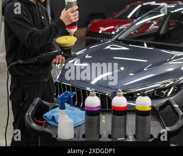 Il master applica una composizione speciale al dispositivo per la lucidatura della superficie della carrozzeria della vettura. Foto Stock