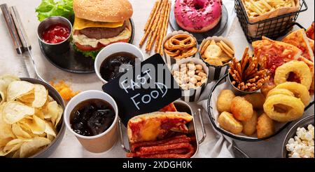 Vari piatti americani, patatine fritte, hamburger, patatine, popcorn, spuntini e salse su sfondo bianco, vista dall'alto. Foto Stock