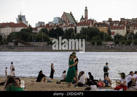 Una coppia abbraccia la spiaggia che si affaccia sulla città Vecchia durante la celebrazione Kupalle (notte di Kupala o notte di mezza estate) sulle rive del fiume Vistola a Varsavia. Diverse centinaia di rappresentanti della diaspora bielorussa a Varsavia si sono riuniti per celebrare Kupalle (o notte di Kupala) sulla riva destra del fiume Vistola. Kupalle è una delle principali feste popolari in Bielorussia. Celebrata come Midsummer (notte di mezza estate), Kupalle è un evento tradizionale che segna la stagione estiva e si svolge il giorno o vicino alla data del solstizio d'estate. Dopo una significativa ondata di immigrazione politica dalla Bielorussia Foto Stock