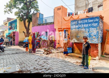 Agra, India - 8 novembre 2018: Splendida vista sulla strada nel centro storico. Case colorate e serbatoio di acqua potabile pubblico. Foto Stock