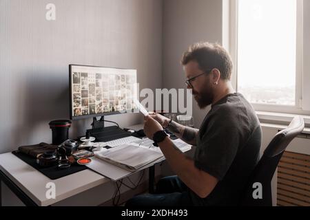 Fotografo che rivede i negativi cinematografici in una workstation moderna Foto Stock