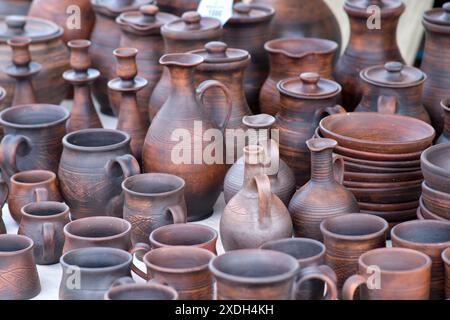 Un tavolo pieno di ceramiche marroni, con tazze, ciotole e vasi. La ceramica è di varie forme e dimensioni ed è in vendita Foto Stock