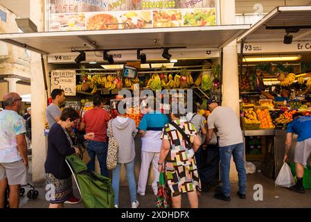 I clienti attendono di essere assistiti in una bancarella di vendita di frutta in un mercato a Cadice, in Spagna. Foto Stock