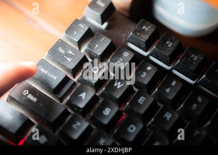 Primo piano del dito di una persona premendo il tasto i'D su una tastiera polverosa e retroilluminata con illuminazione multicolore. Foto Stock