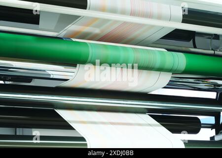 Un rotolo di carta stampato su una macchina. I rotoli di carta sono impilati l'uno sull'altro e la macchina è sullo sfondo Foto Stock