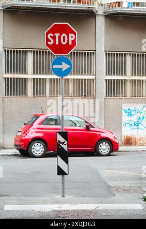 Cremona, Italia - 21 giugno 2024 auto rossa parcheggiata sul lato della strada con segnale di stop e svolta a destra solo in ambiente urbano Foto Stock