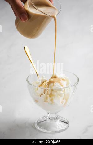 Un primo piano verticale di affogato preparato con espresso versato su gelato alla vaniglia in una tazza di vetro su sfondo bianco Foto Stock
