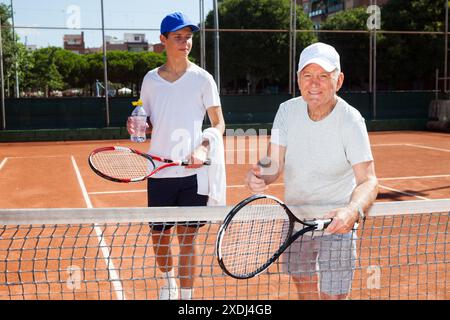 Nonno e nipote in posa sul campo da tennis Foto Stock