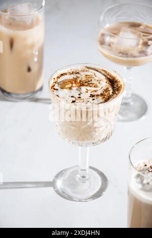 Uno shot verticale di varie bevande a base di caffè ghiacciato in bicchieri eleganti su sfondo bianco Foto Stock