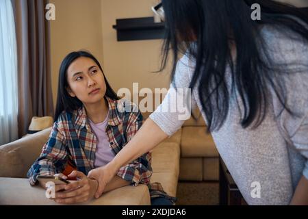 Genitore che impedisce a sua figlia adulta di usare lo smartphone in modo eccessivo Foto Stock