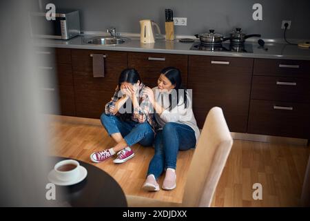 Una donna sconvolta che viene confortata da una madre amorevole Foto Stock