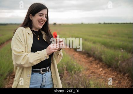 Ragazza sorridente con papavero rosso in un meraviglioso campo di lavanda Foto Stock