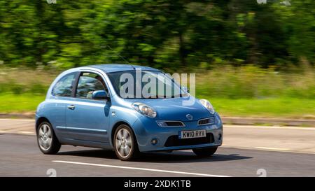 Milton Keynes, Regno Unito - 21 giugno 2024: 2010 auto blu Nissan Micra che guida su una strada di campagna britannica Foto Stock