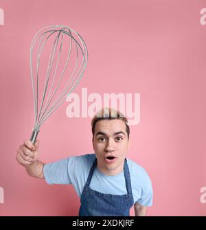 Pasticcere con frusta grande su sfondo rosa Foto Stock