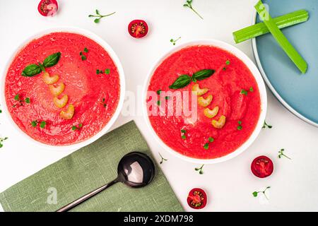 Zuppa di gazpacho in ciotole su sfondo chiaro. Zuppa di crema di pomodoro con basilico e sedano. Il concetto di mangiare sano. Vista dall'alto. ph di alta qualità Foto Stock