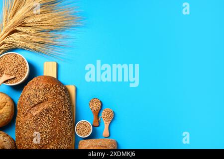 Pan di pane fresco con panini, ciotole, spikelets di grano e grani su sfondo blu Foto Stock