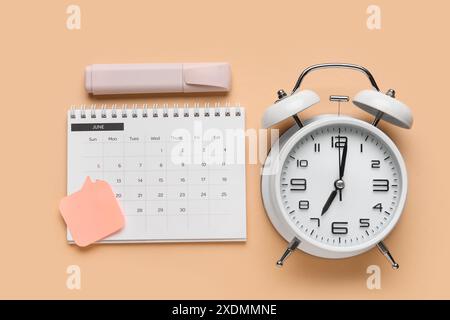 Calendario con sveglia e cancelleria su sfondo beige Foto Stock