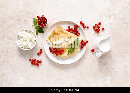 Crepes o pancake sottili con cottage di formaggio o cagliata e frutti di ribes rosso freschi, vista dall'alto Foto Stock