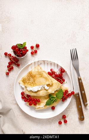 Crepes o pancake sottili con cottage di formaggio o cagliata e frutti di ribes rosso freschi, vista dall'alto Foto Stock