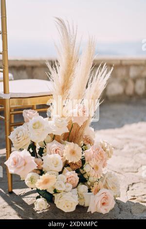 Un bouquet di fiori si trova vicino a una sedia in un'area aperta Foto Stock