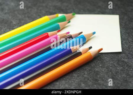 Matite in diversi colori e clip su sfondo grigio Foto Stock