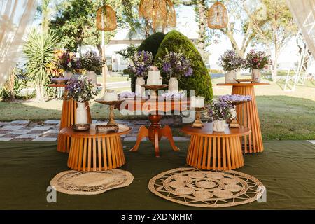 Splendida decorazione per matrimoni all'aperto con tavoli in legno, composizioni floreali e candele sotto un baldacchino. Foto Stock