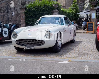 Castellarquato, Italia - 22 giugno 2024 Rally bandiera Argento , auto da corsa bianca parcheggiata su ciottoli trasuda lusso e stile, mostrando un des senza tempo Foto Stock