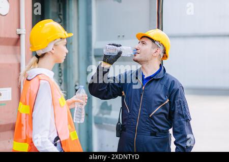 Felice ingegnere lavoratore del team assetato acqua potabile freno rilassarsi lavoro sano in estate calda nel settore del trasporto marittimo portuale. Foto Stock