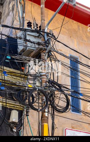 Linee elettriche caotiche e cavi che affollano pali di pubblica utilità a Santa Marta, Colombia. Sovraccarico di infrastrutture urbane nella città sudamericana. Foto Stock