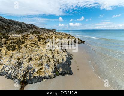 Spiaggia sabbiosa con rocce coperte di barnacle e alghe a Port a Chapuill sulla remota isola Ebridea di Colonsay a giugno, Scozia, Regno Unito Foto Stock