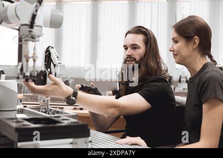 Programma di robotica industriale studenti universitari che imparano l'assemblaggio meccanico con robot Universal Training Platform mod di simulazione braccio robotico Foto Stock