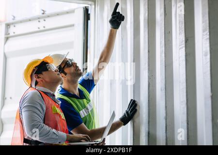 Il team di ingegneri dell'autorità portuale controlla le condizioni dell'armadietto del contenitore di carico per la sicurezza in conformità alla regola e agli standard intermodali. Foto Stock