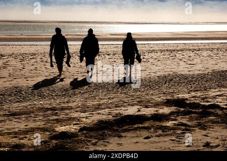 Tre escursionisti che si stagliano al tramonto sulla spiaggia di Aberdovey, Aberdyfi, (Aberdovey), Gwynedd, Galles, Regno Unito Foto Stock